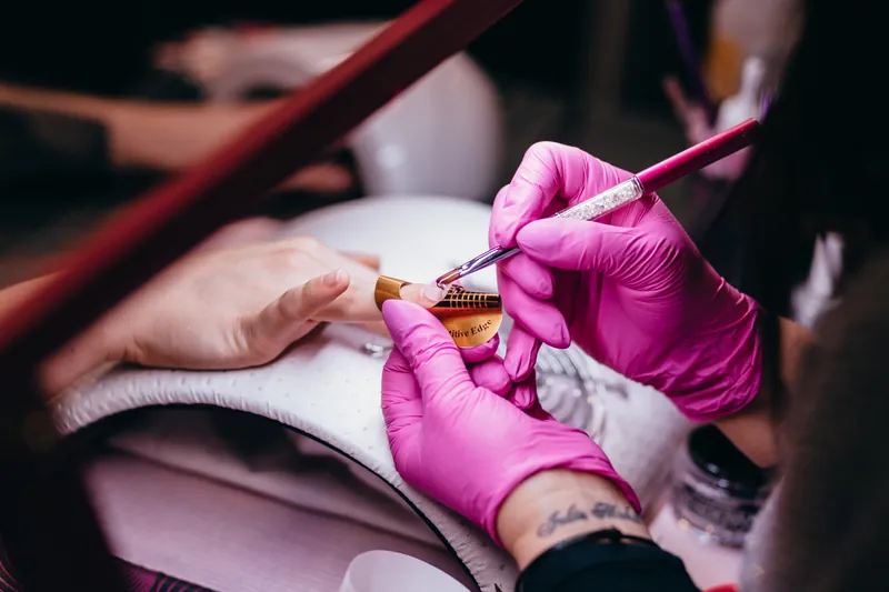 Schoonheidsspecialiste brengt met een fijn penseel lak aan op de nagels van een klant